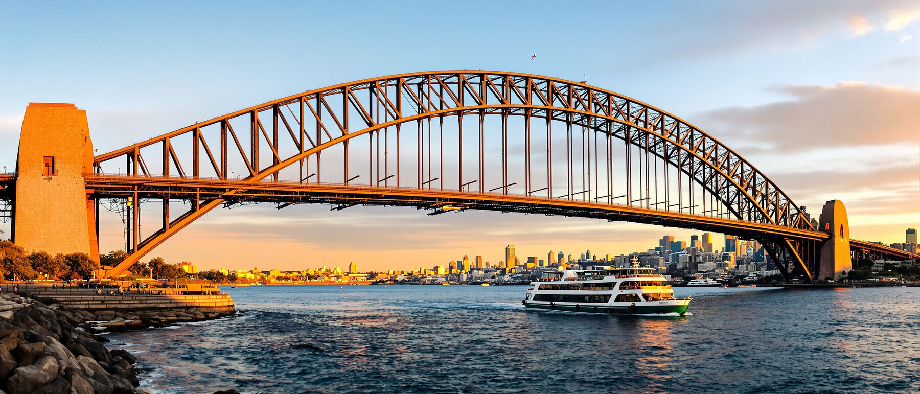 Sydney Harbour Bridge at golden hour with a ferry crossing the harbour below the steel arch